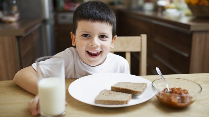 Chłopiec pijący mleko i jedzący śniadanie